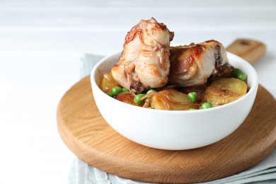 Tasty cooked rabbit with vegetables in bowl on white table, closeup. Space for text