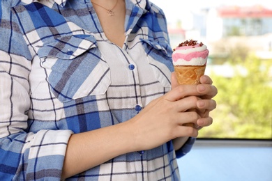 Photo of Woman holding yummy ice cream on blurred background. Focus on hands