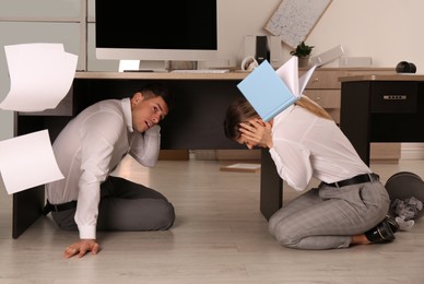 Scared employees on floor in office during earthquake