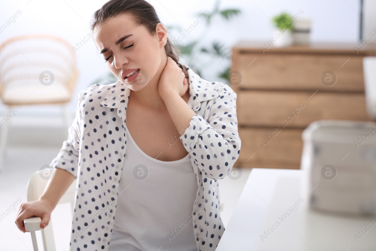 Photo of Woman suffering from neck pain in office. Bad posture problem