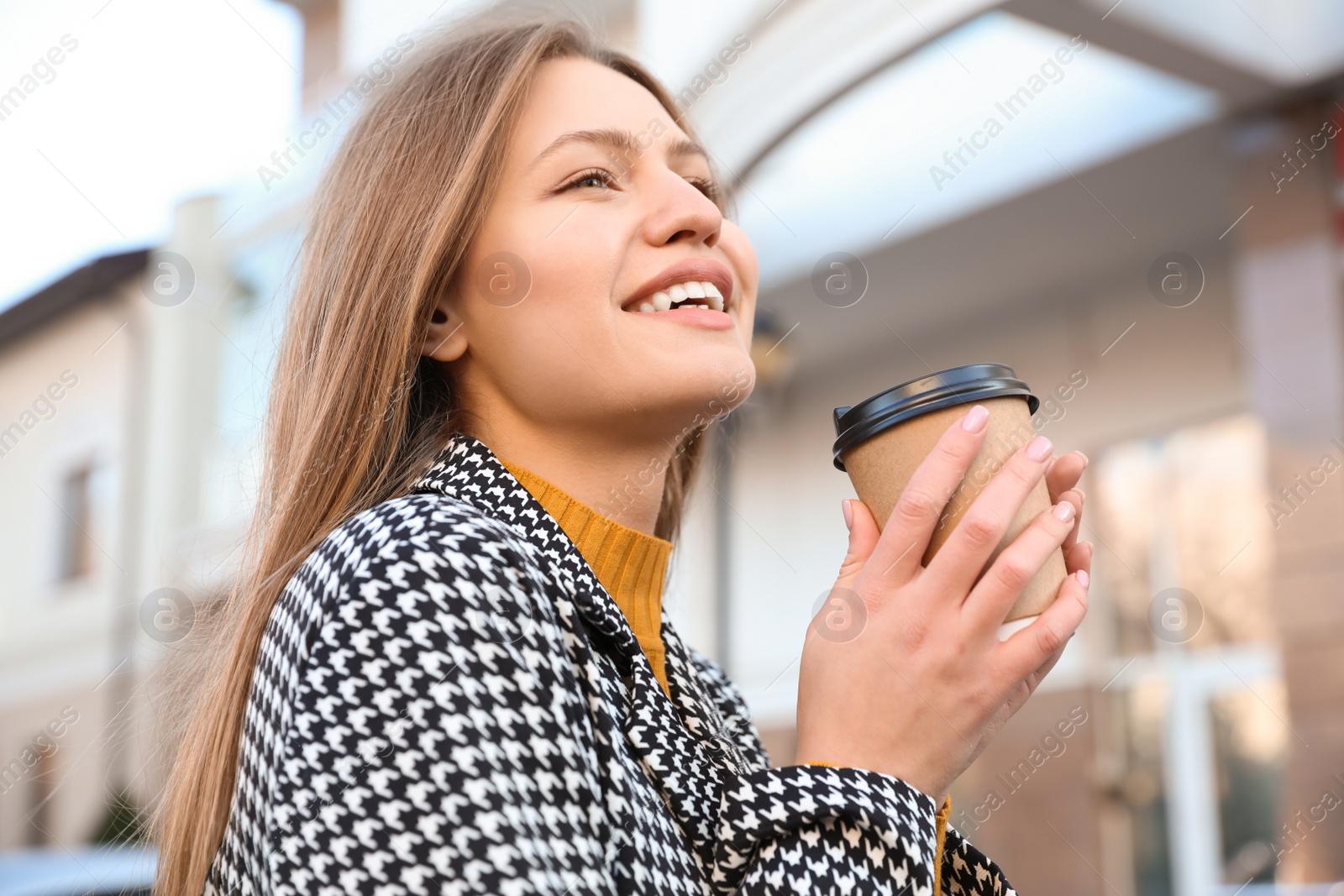 Photo of Young woman with cup of coffee on city street in morning