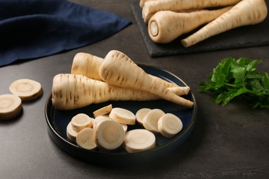 Whole and cut parsnips on black table