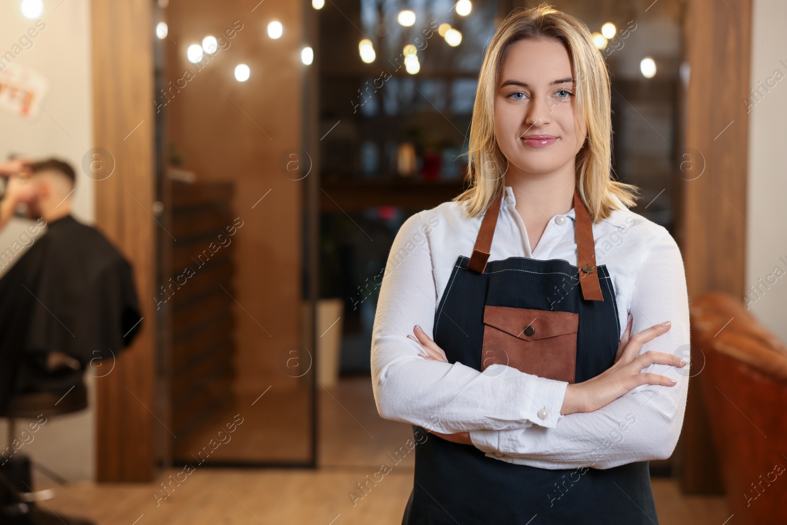 Photo of Portrait of professional hairdresser wearing apron in beauty salon, space for text