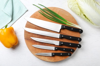 Flat lay composition with set of different knives on white wooden table