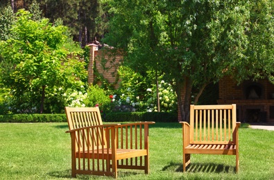 Wooden armchairs in beautiful garden on sunny day
