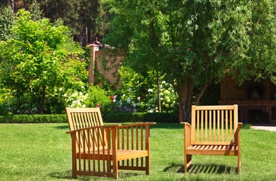 Photo of Wooden armchairs in beautiful garden on sunny day