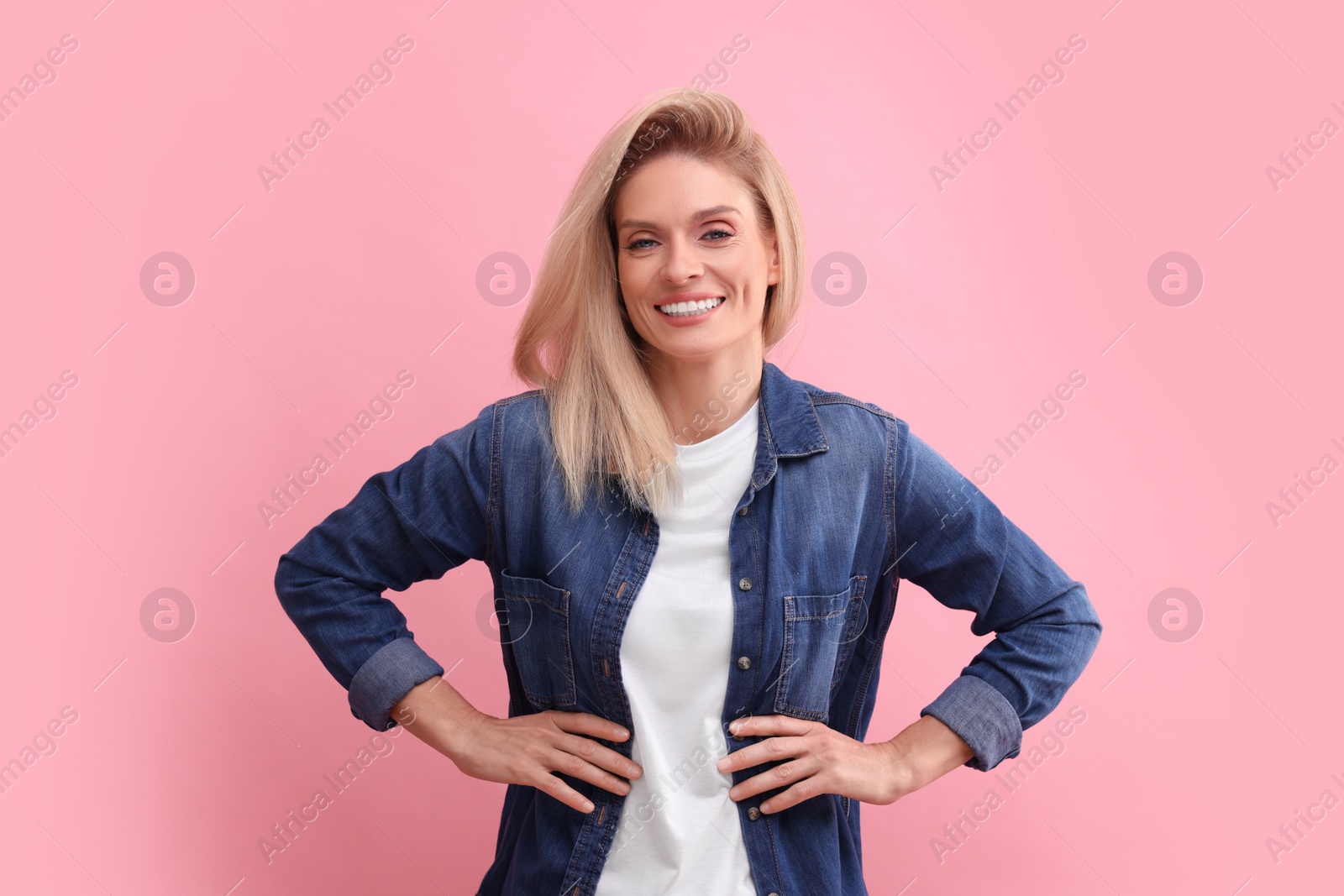 Photo of Portrait of smiling middle aged woman with blonde hair on pink background