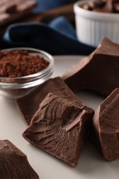 Photo of Pieces of tasty milk chocolate and powder on plate, closeup