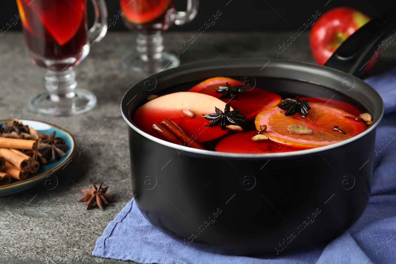 Photo of Delicious mulled wine and ingredients on grey table, closeup