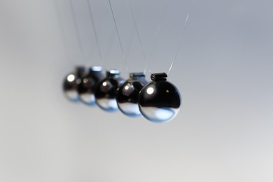 Photo of Newton's cradle on grey background, closeup. Physics law of energy conservation