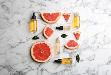 Photo of Flat lay composition with grapefruit slices and bottles of essential oil on marble background