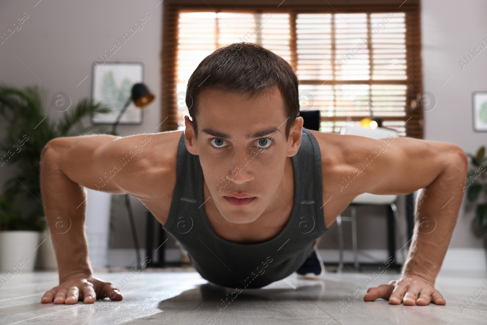 Photo of Handsome man doing plank exercise on floor at home