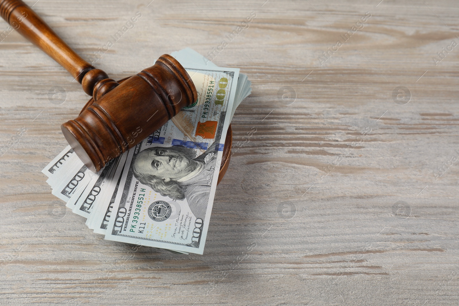 Photo of Judge's gavel and money on wooden table. Space for text