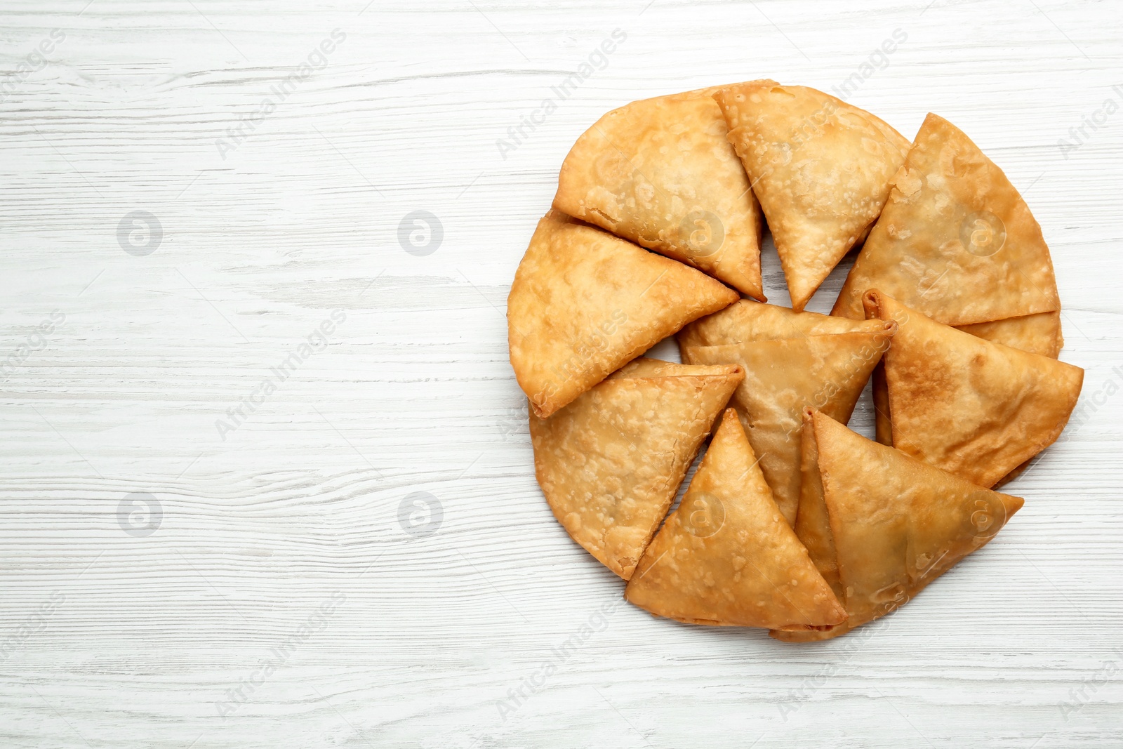 Photo of Fresh delicious crispy samosas on white wooden table, flat lay. Space for text