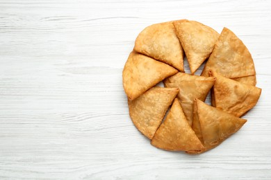 Photo of Fresh delicious crispy samosas on white wooden table, flat lay. Space for text