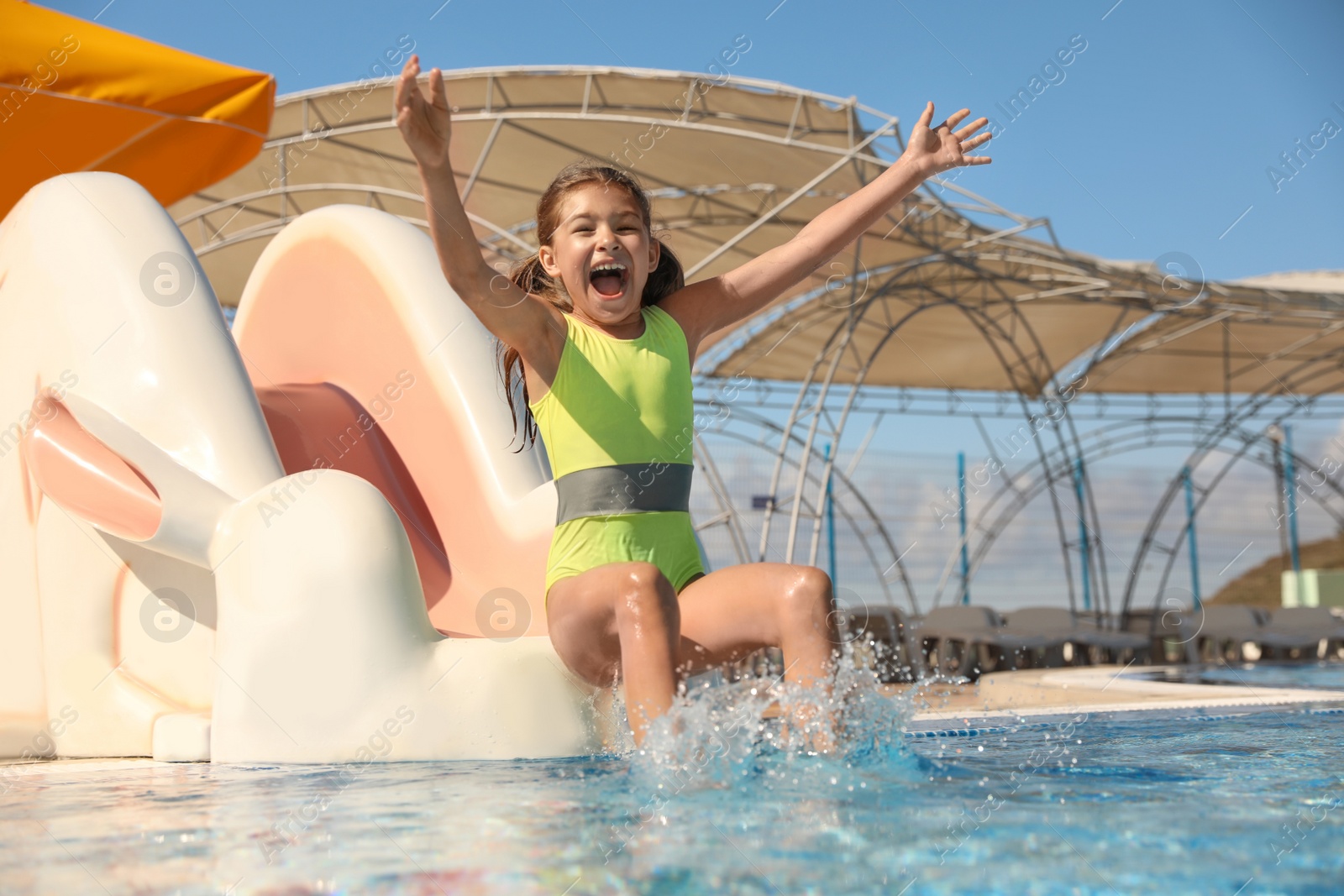 Photo of Happy girl on slide at water park. Summer vacation