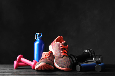 Photo of Gym equipment and accessories on wooden floor against dark background