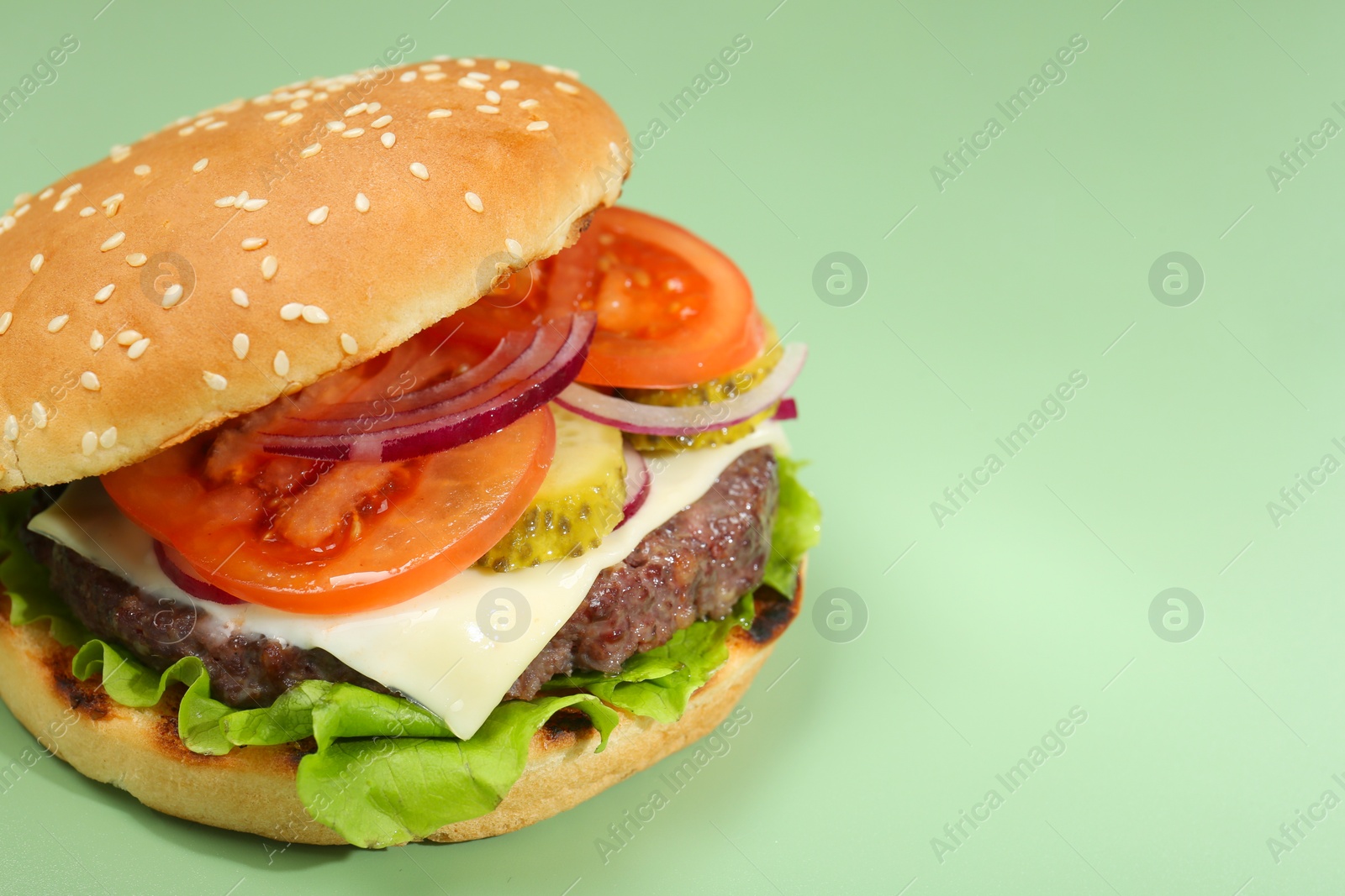 Photo of Burger with delicious patty on green background, closeup. Space for text