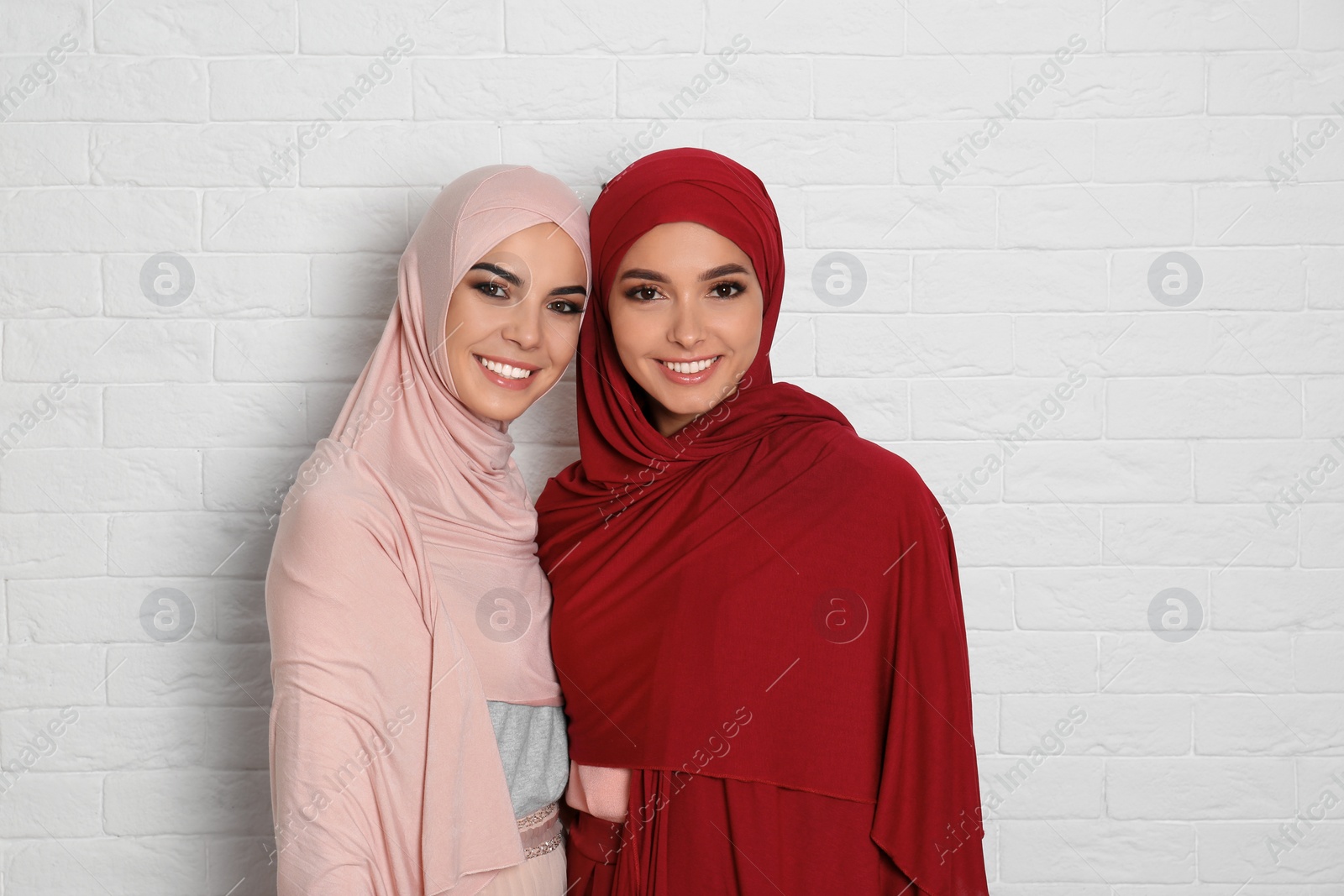 Photo of Portrait of young Muslim women in hijabs against brick wall