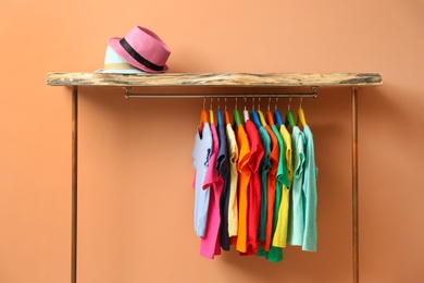Rack with different child's clothes near coral wall