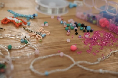 Photo of Beautiful handmade beaded jewelry and supplies on wooden table