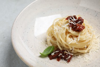 Photo of Tasty spaghetti with sun-dried tomatoes and cheese served on light grey table, closeup. Exquisite presentation of pasta dish