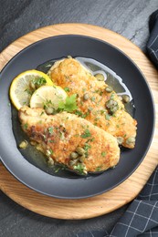 Delicious chicken piccata on black table, top view