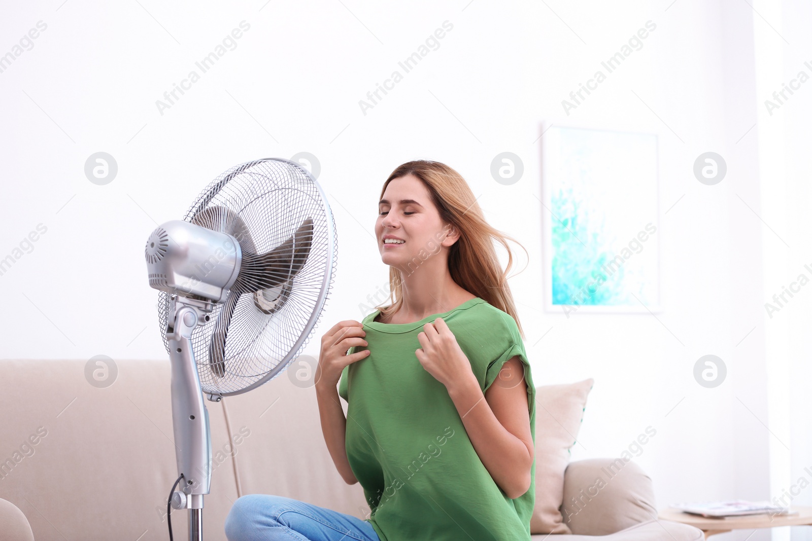 Photo of Woman refreshing from heat in front of fan at home