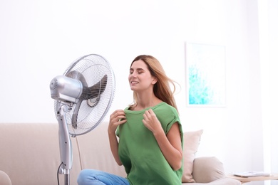 Woman refreshing from heat in front of fan at home