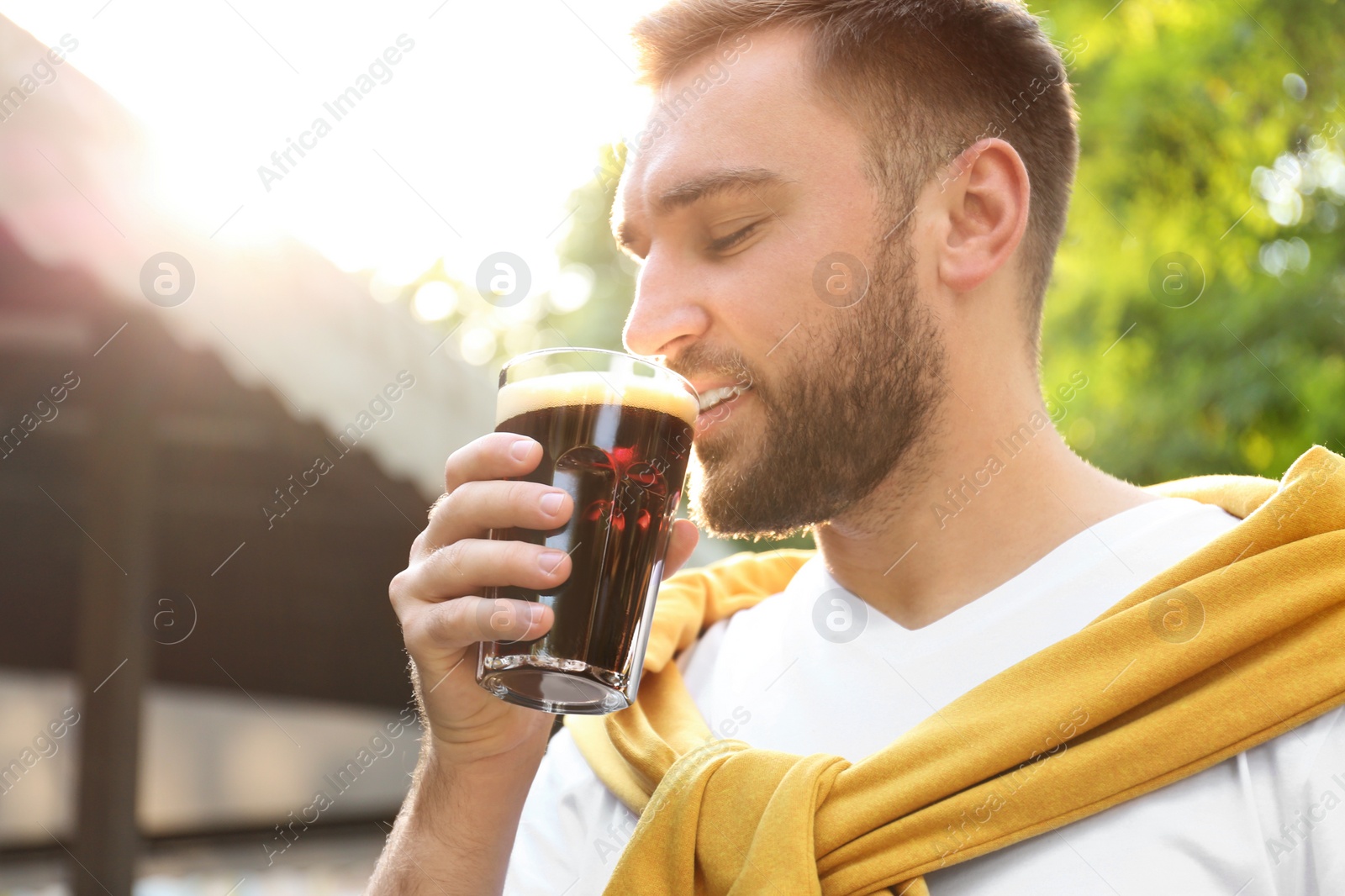 Photo of Handsome man with cold kvass outdoors. Traditional Russian summer drink