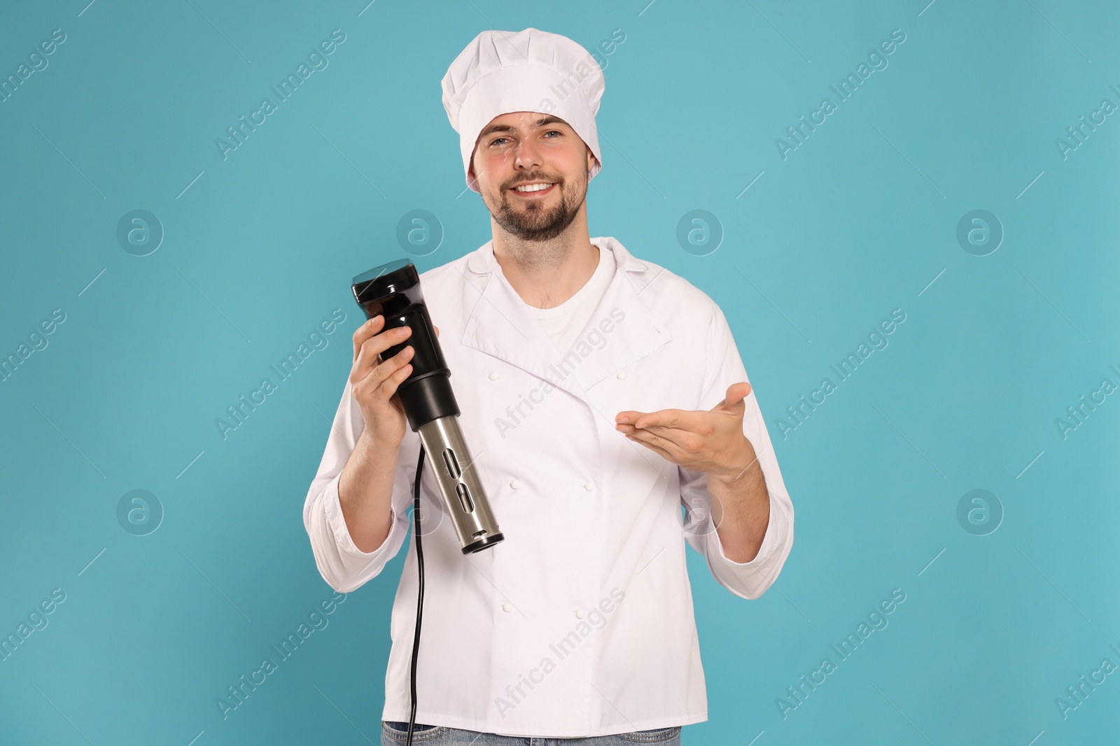 Photo of Smiling chef holding sous vide cooker on light blue background