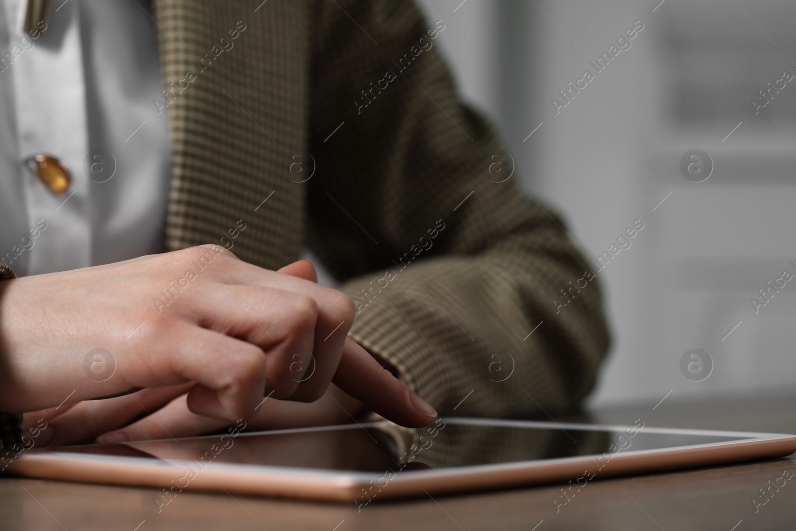 Photo of Closeup view of woman using modern tablet at table on blurred background