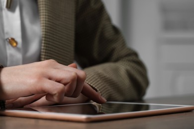 Photo of Closeup view of woman using modern tablet at table on blurred background