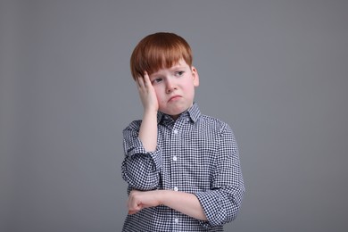 Portrait of sad little boy on grey background