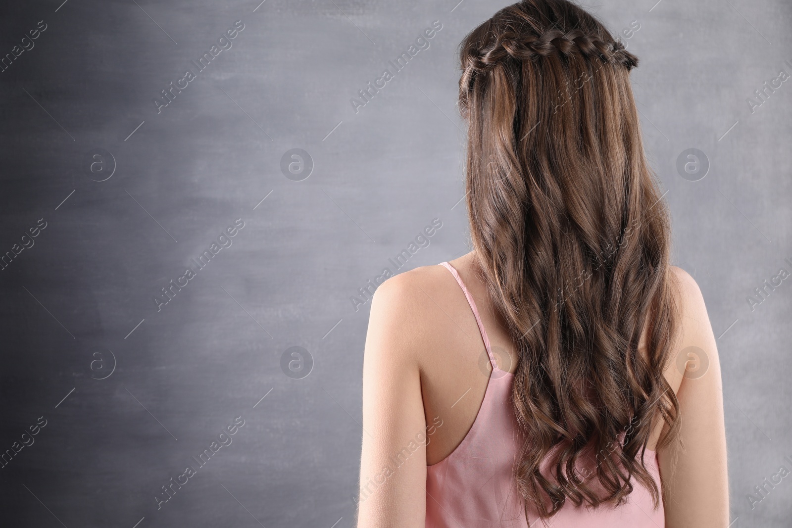 Photo of Woman with braided hair on grey background, back view. Space for text