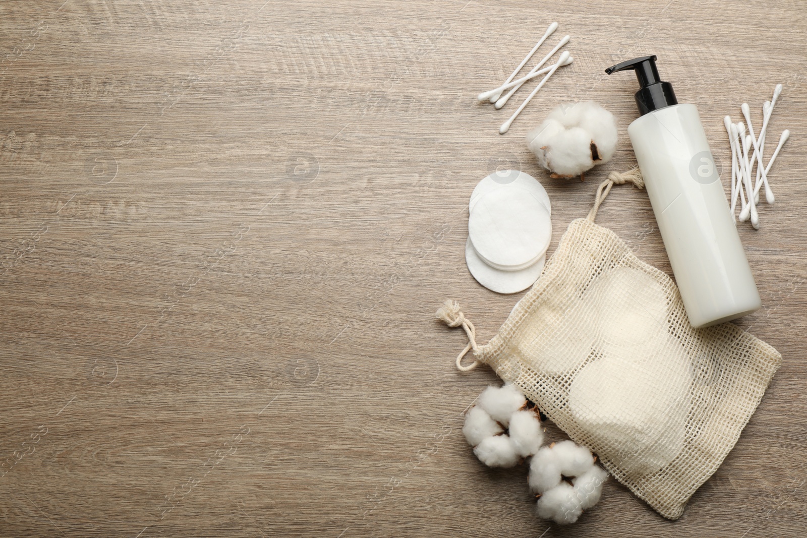 Photo of Cotton pads, swabs and makeup removal product on wooden table, flat lay. Space for text