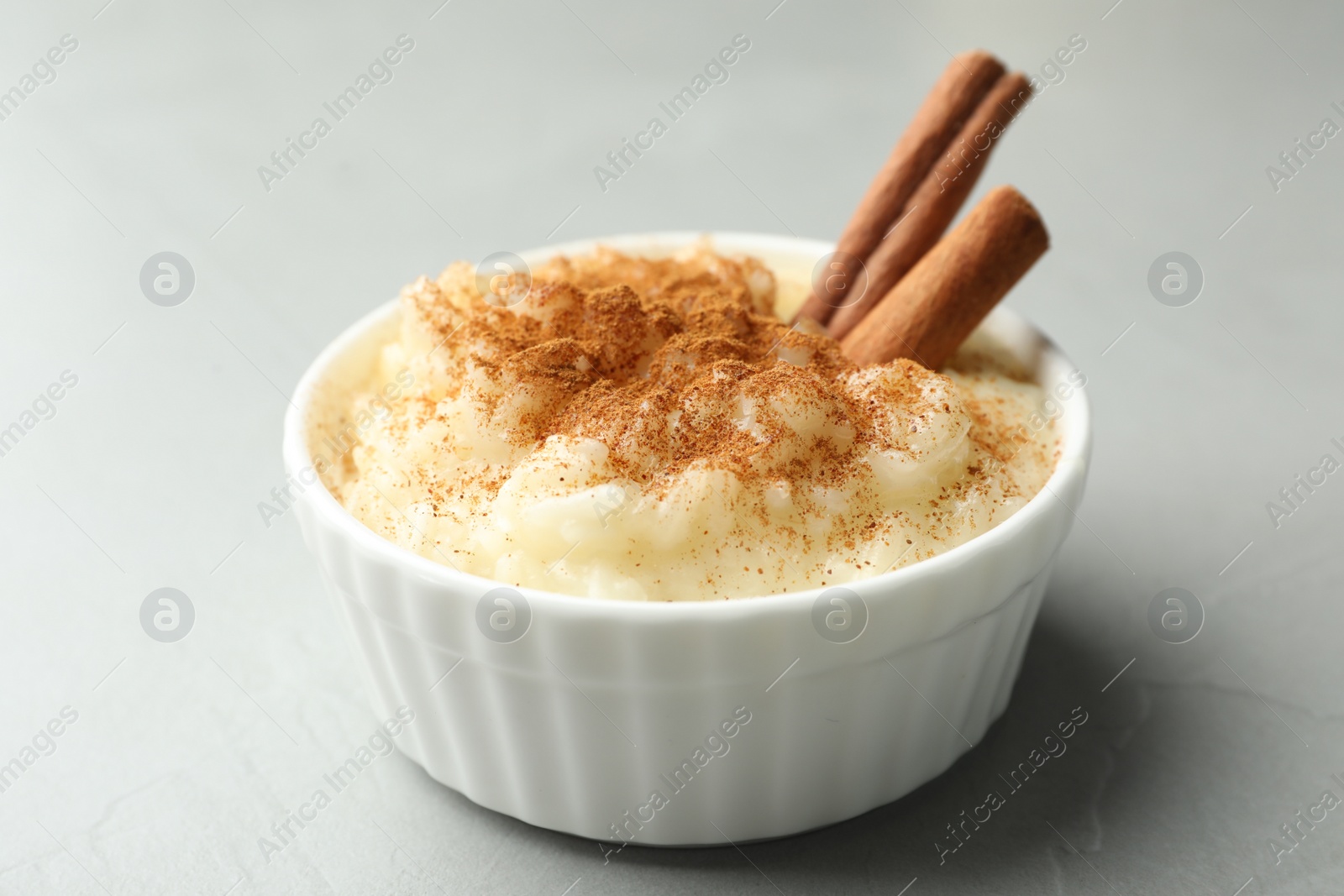 Photo of Delicious rice pudding with cinnamon on light table, closeup