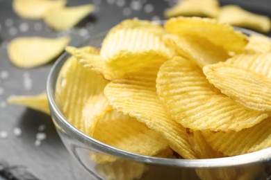 Tasty potato chips in bowl, closeup view