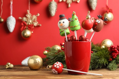 Photo of Delicious Christmas themed cake pops and festive decor on wooden table