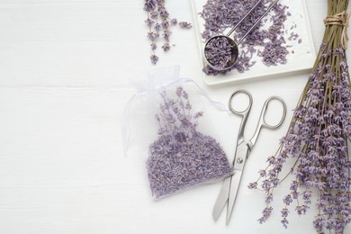 Scented sachet with dried lavender flowers and scissors on white wooden table, flat lay. Space for text