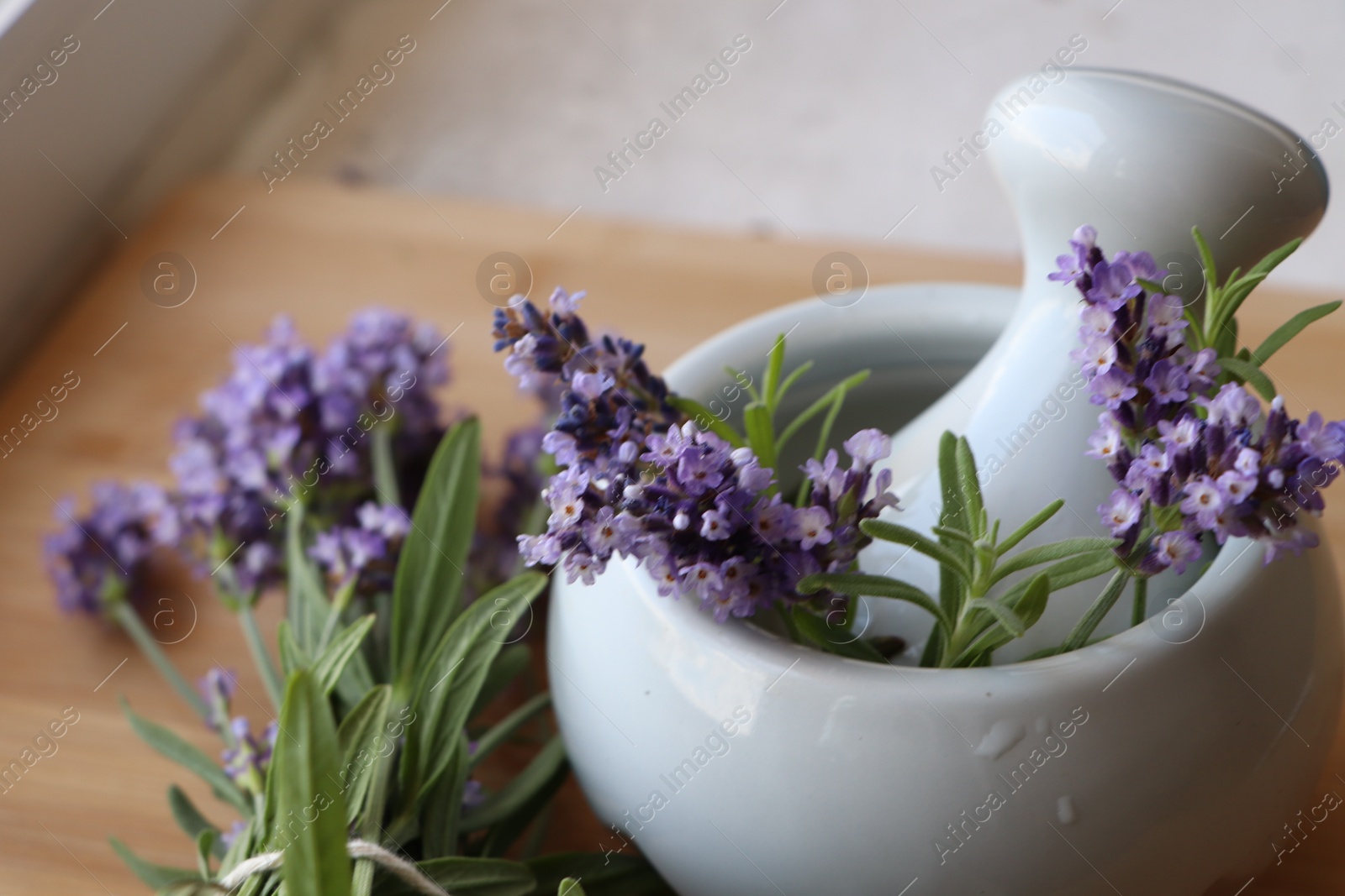 Photo of Mortar with fresh lavender flowers, rosemary and pestle on table, closeup. Space for text