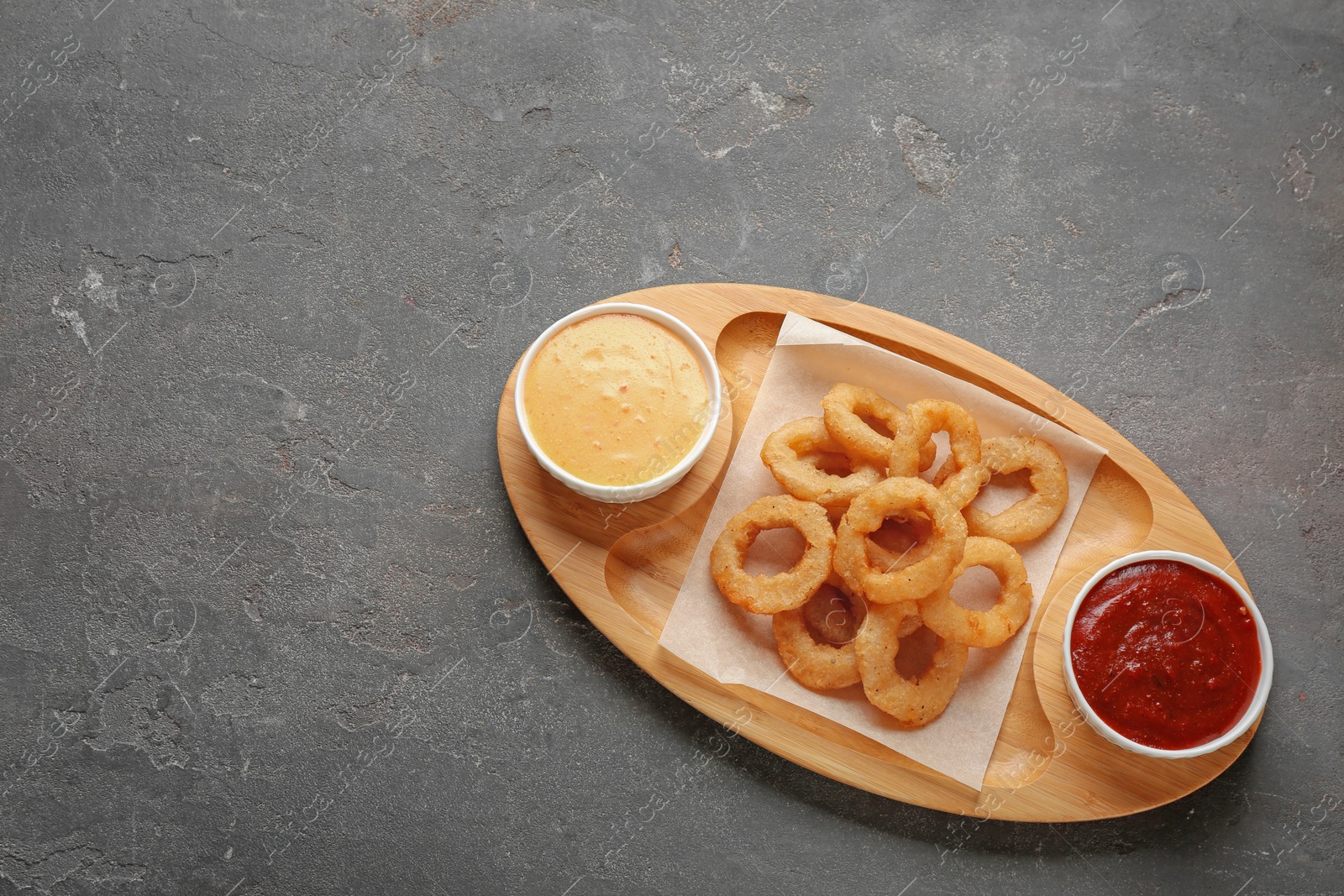 Photo of Plate with fried onion rings and sauces served on table, top view