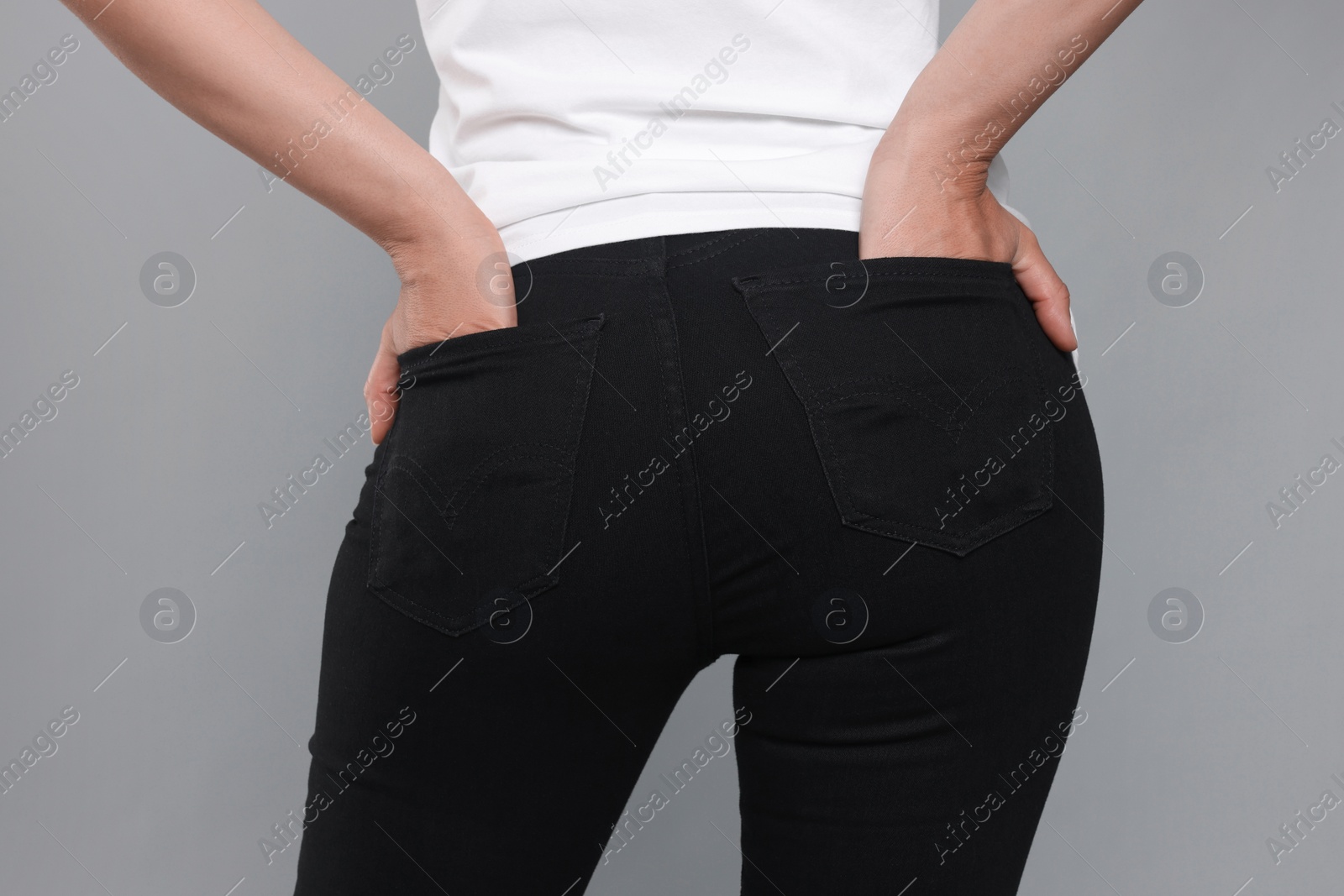 Photo of Woman wearing stylish black jeans on light gray background, closeup