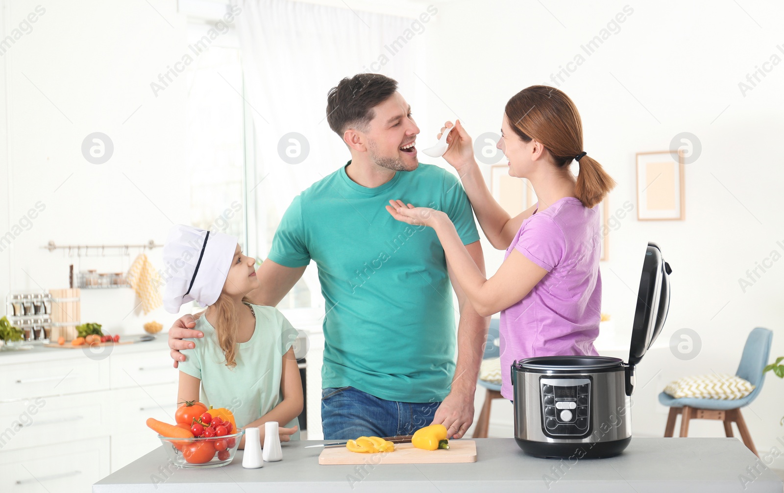 Photo of Happy family preparing food with modern multi cooker in kitchen