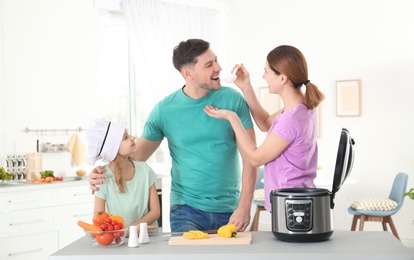 Happy family preparing food with modern multi cooker in kitchen