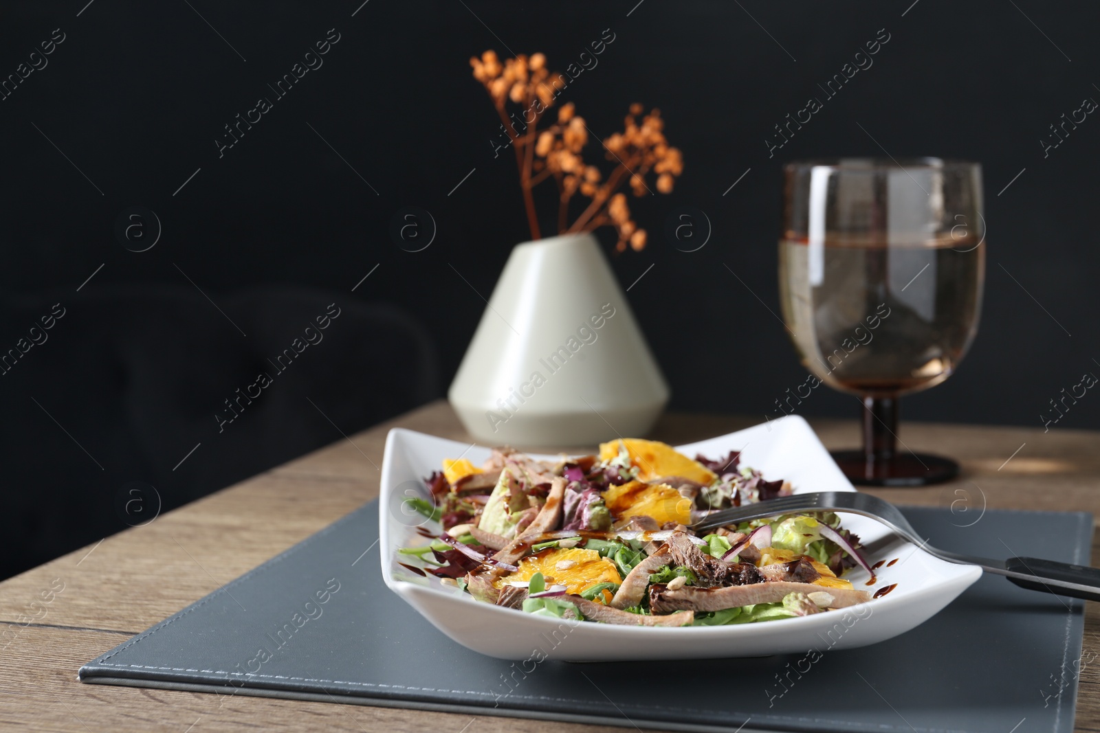 Photo of Delicious salad with beef tongue, orange, onion and fork served on wooden table