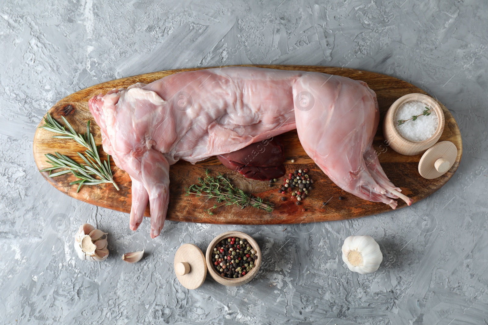 Photo of Whole raw rabbit, liver and spices on grey textured table, top view