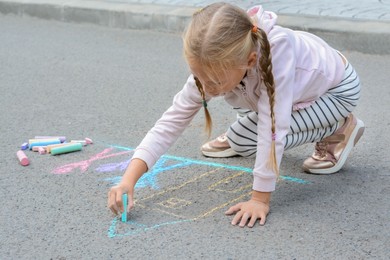 Little child drawing happy family with chalk on asphalt