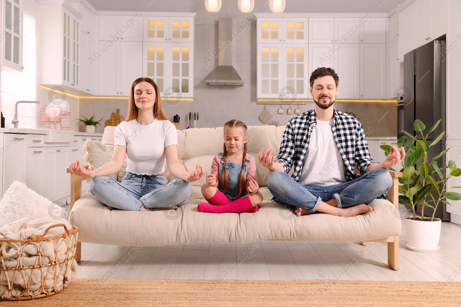 Photo of Family meditating together on sofa at home. Harmony and zen