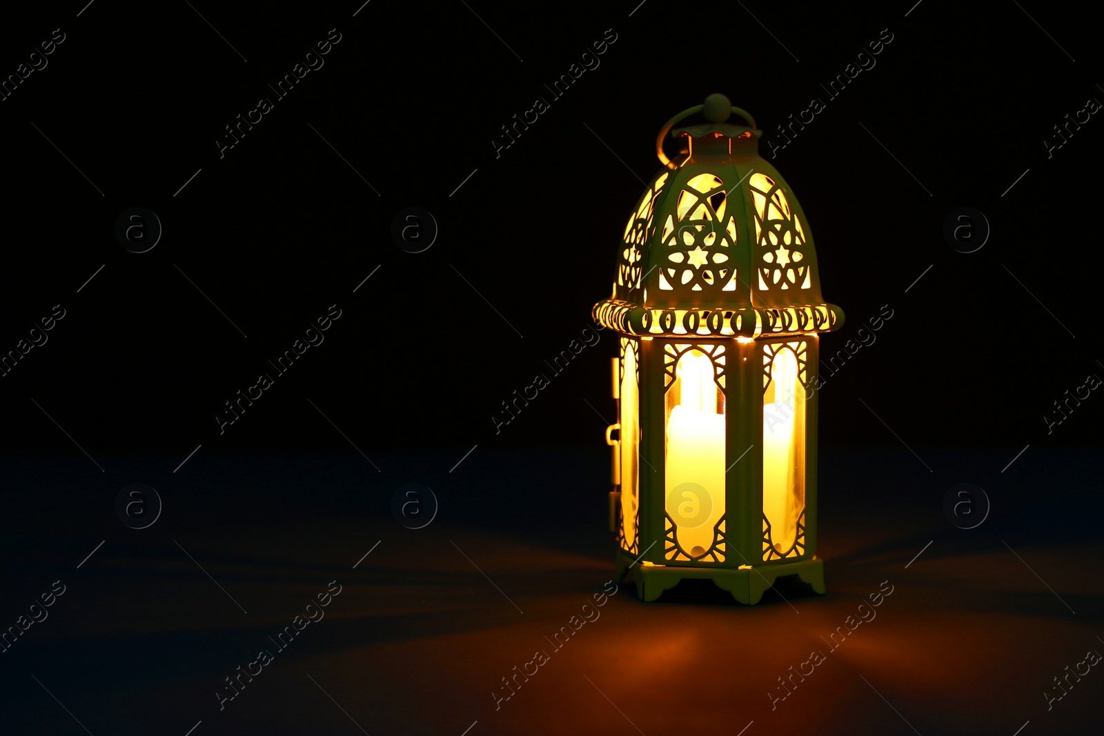 Photo of Decorative Arabic lantern on table against dark background. Space for text